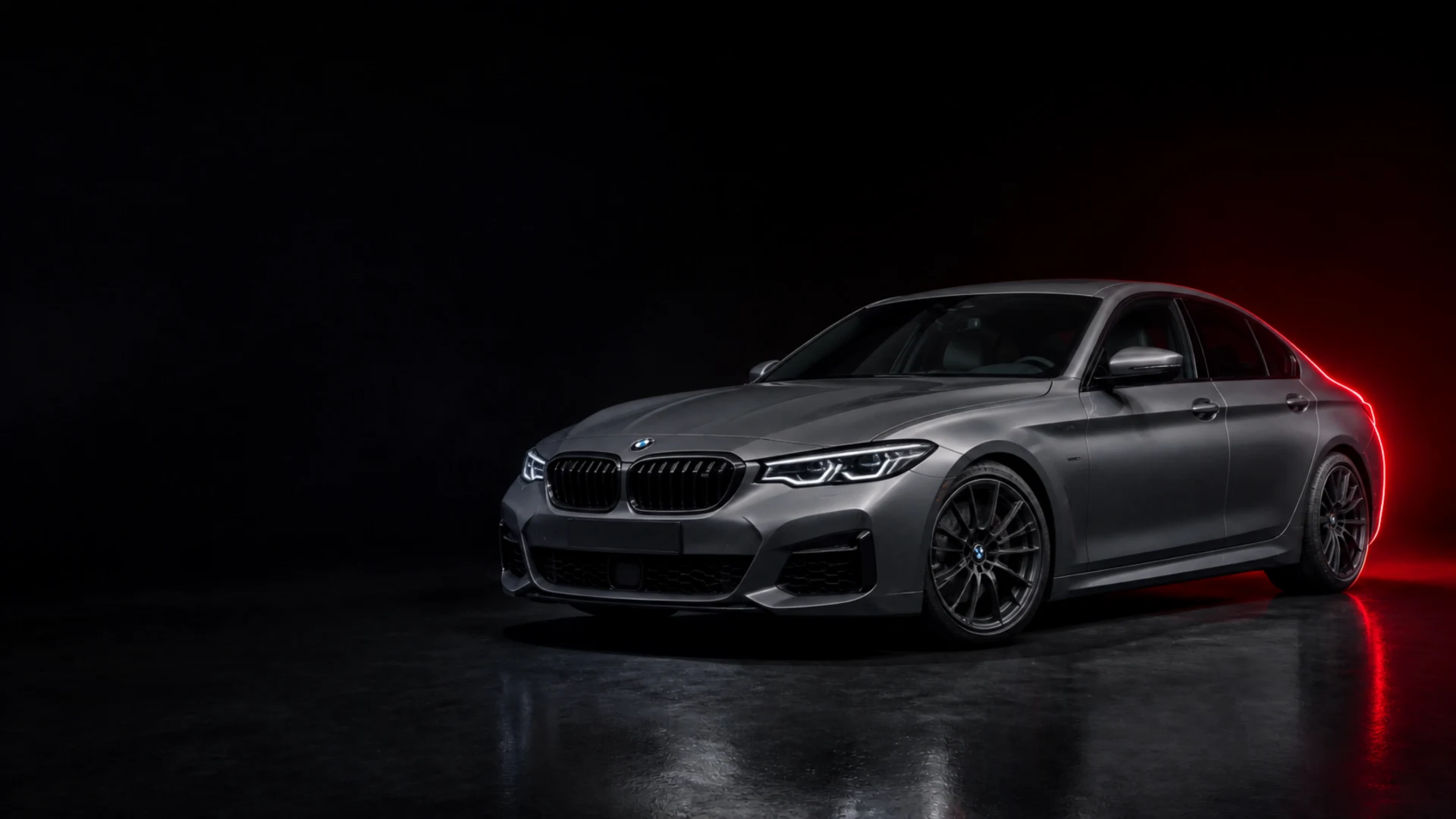 Grauer BMW im dunklen Studio mit rotem Licht, Symbolbild KI-generiert