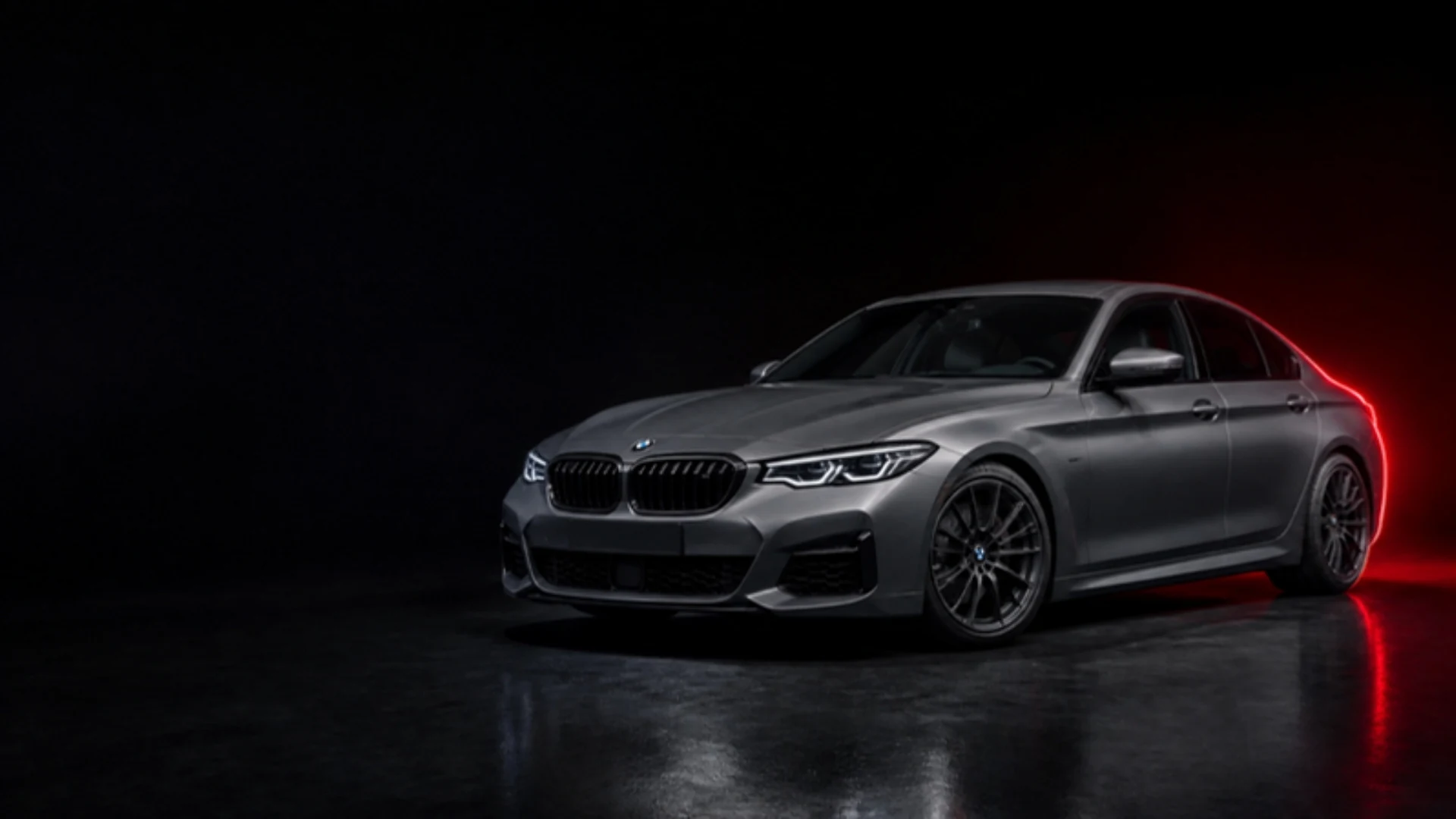 Grauer BMW im dunklen Studio mit rotem Licht, Symbolbild KI-generiert